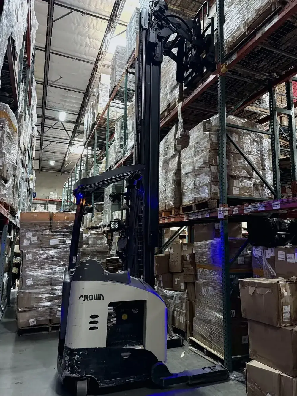 Reach truck working beside warehouse racking