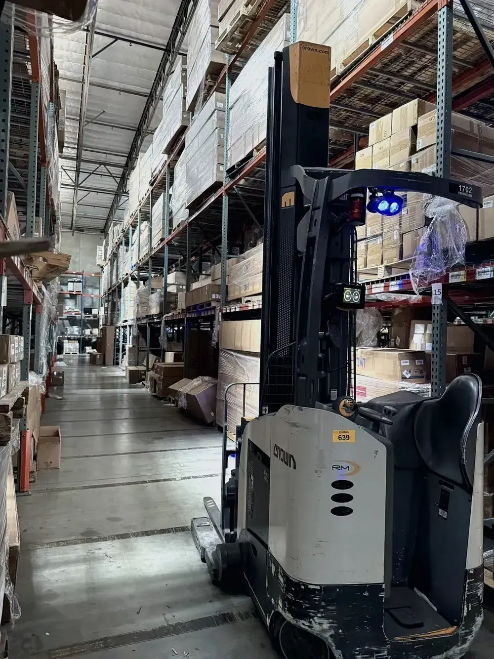 Operator driving a reach truck through warehouse aisles